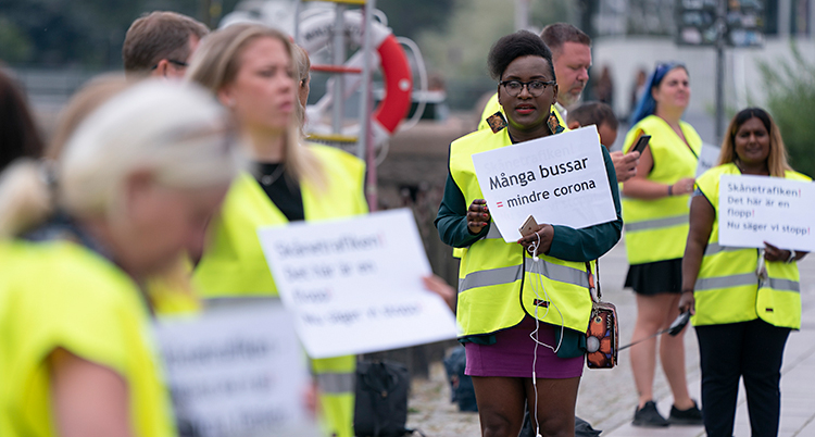 Bilden är tagen utomhus. Vi ser personer som protesterar. De har gula västar på sig. Och skyltar där det står olika saker.