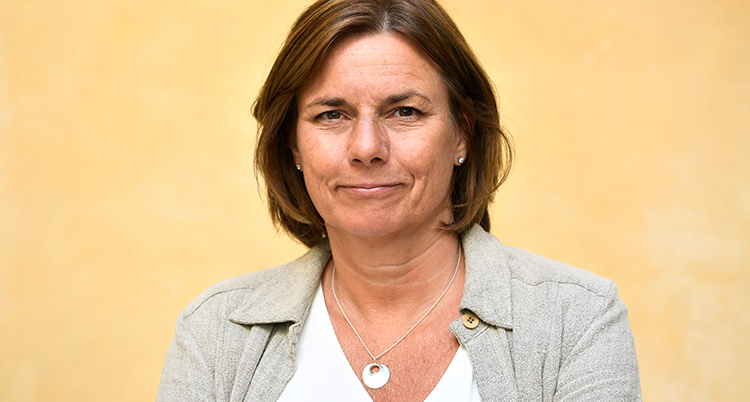 Lövin står framför en gul vägg. Hon har brunt hår till axlarna och ser nöjd ut