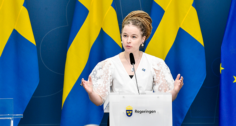 Kulturminister Amanda Lind pratar på en presskonferens. Bakom hennes syns en svensk flagga.