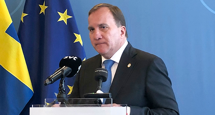 Löfven står i en talarstol. Han ser sammanbiten ut.
