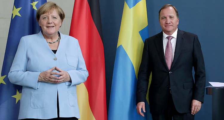 ANgela Merkel och Löfven framför EUs Tysklands och Sveriges flaggor. De ser glada ut.