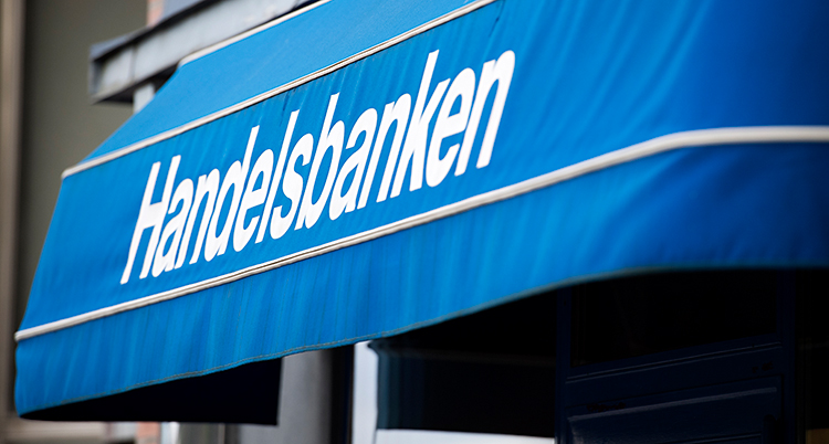 Vi ser en blå markis utanför ett kontor. Markisen är blå. Det står Handelsbanken på den.
