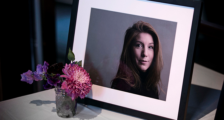 Ett inramat foto på Kim Wall på en bänk. Framför står en liten glasvas med en blomma.