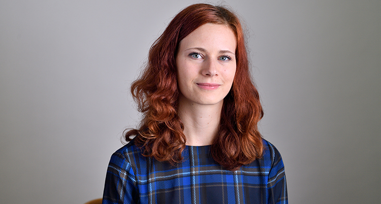 Rebecka le Moine har rött axellångt hår och blårutig skjorta. Hon tittar in i kameran och ler.