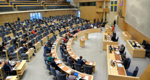 En bild på plenisalen i riksdagen. Där politikerna sitter.