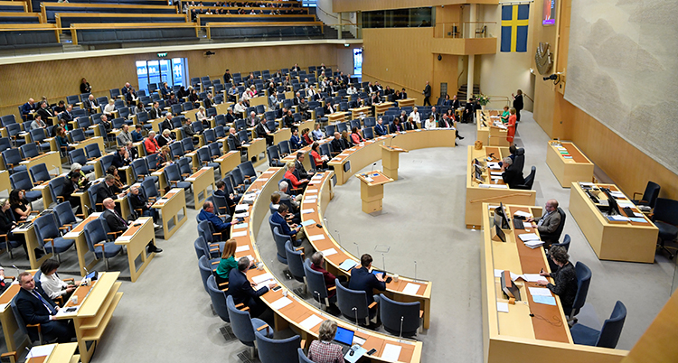 En bild på plenisalen i riksdagen. Där politikerna sitter.