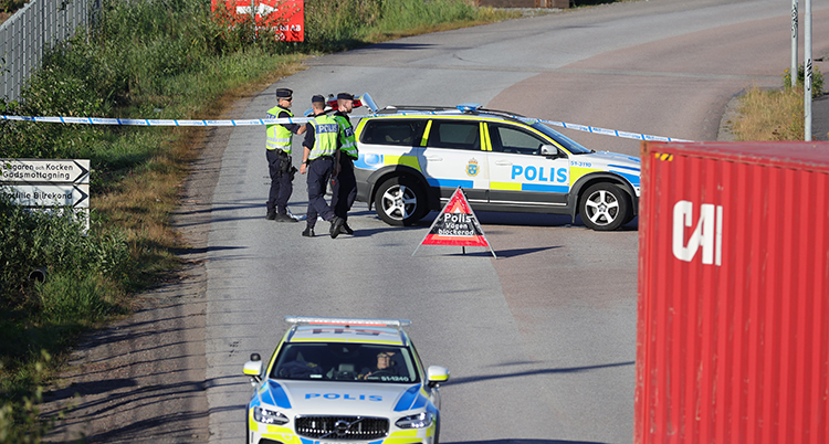 Två polisbilar och flera poliser syns på platsen. De sätter upp tejp för att stänga området.
