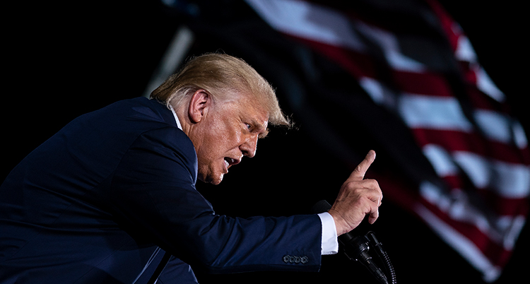 Trump ser arg ut. Han talar och håller upp ett finer i luften.