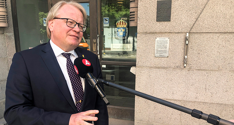 Peter Hultqvist utomhus står och svarar på frågor framför en mikrofon som det står tv4 på.