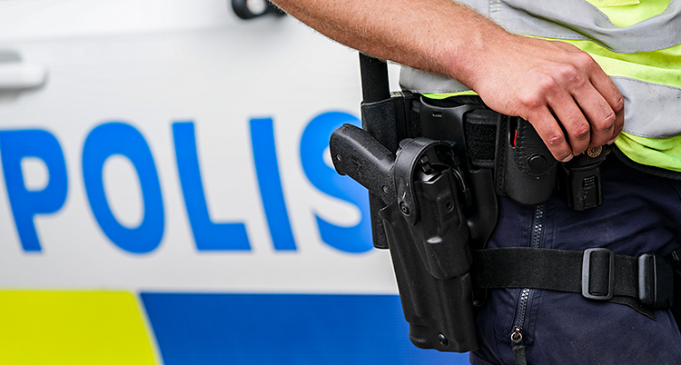 Bilden visar en polis. Vi ser bara armen och pistolen. I bakgrunden syns en polisbild. Det är inte polisen på bilden som nyheten handlar om.
