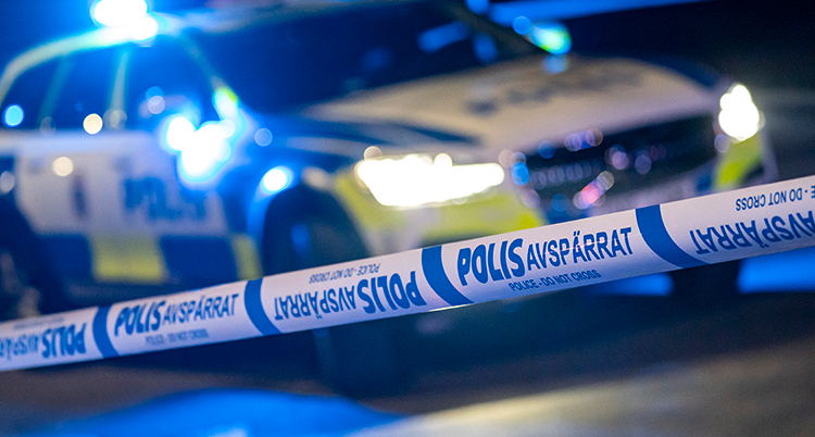Tejp som det står polis på syns. I bakgrunden en polisbil med ljus på.