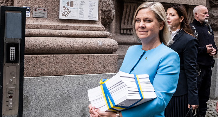 Andersson går med en stor bunt papper och ler.
