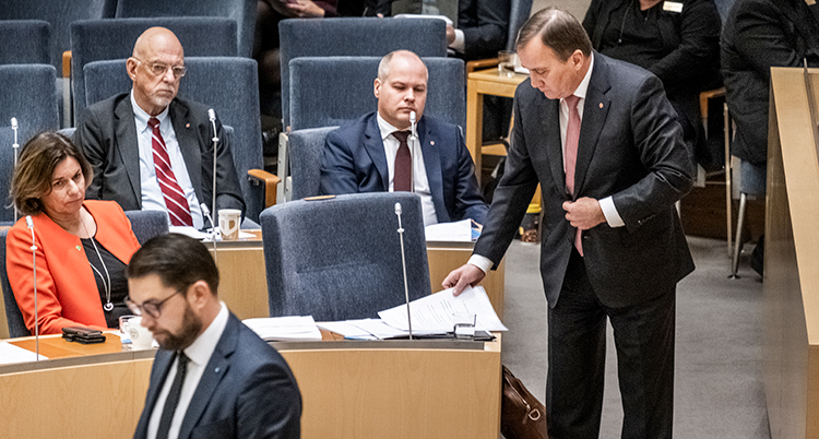 flera politiker i riksdagens lokaler. Statsministern står upp vid sin stol.