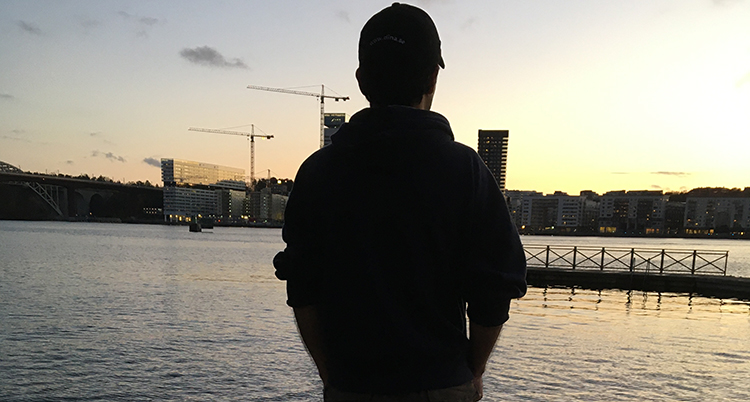 Salem står med ryggen mot fotografen och tittar över ut över vattnet. Solen håller på att gå ned.