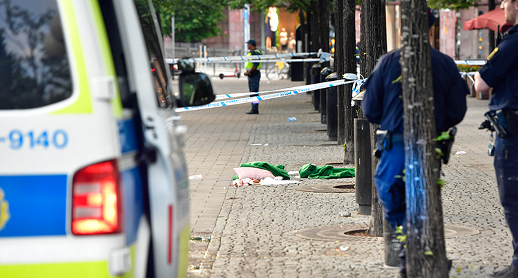 En del av en polisbil syns och tejp som det står polisen på.