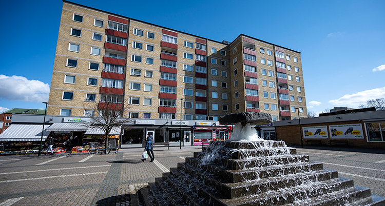 Bilden visar ett torg. På torget finns en fontän som är byggd i flera trappsteg.