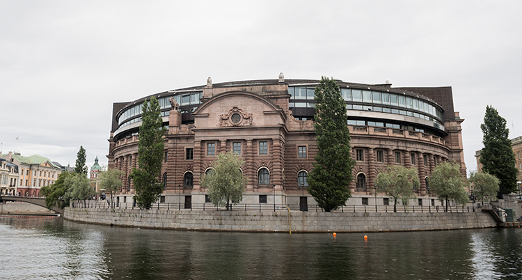 Sveriges riksdag en bit ifrån. Det är ett runt stort hus i sten.