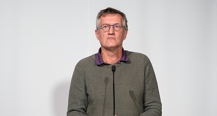 Han ser allvarlig ut. Han pratar i en mikrofon.