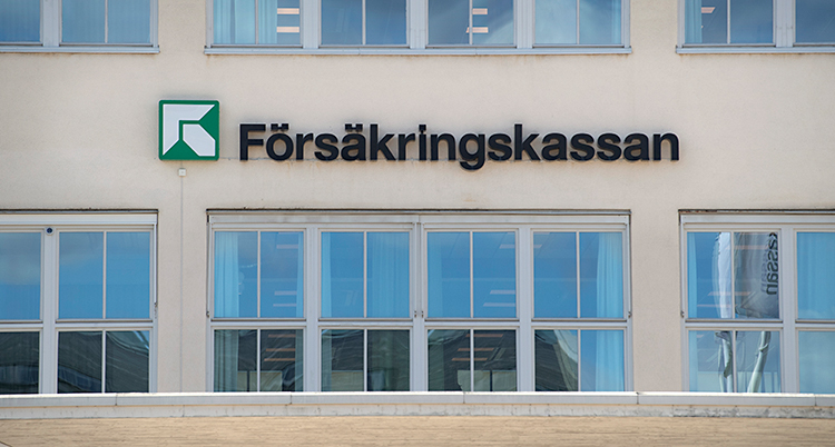 Vi ser utsidan av ett hus. Huset har stora fönster. Mellan fönstren finns en skylt där det står Försäkringskassan.