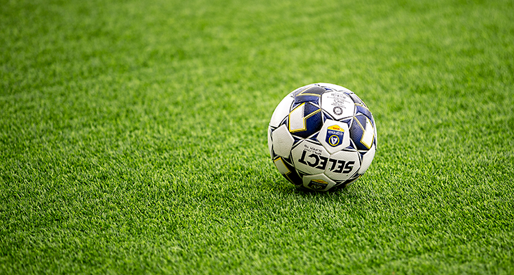 En fotboll ligger på en grön fotbollsplan.