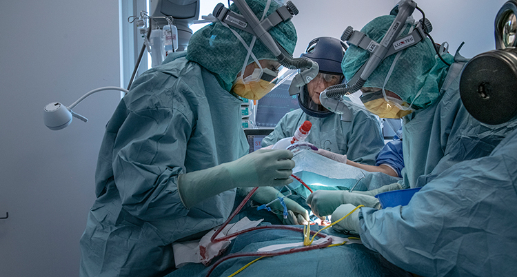 medicinskt personal med skyddskläder opererar på en person.