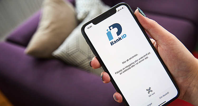 En person håller i en mobiltelefon. På telefonen står det bank-id.