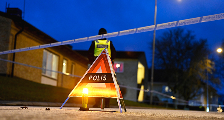 En kon som det står polis på och ett avspärrningsband finns framför ett hus. En polis i reflexväst syns en bit bort.
