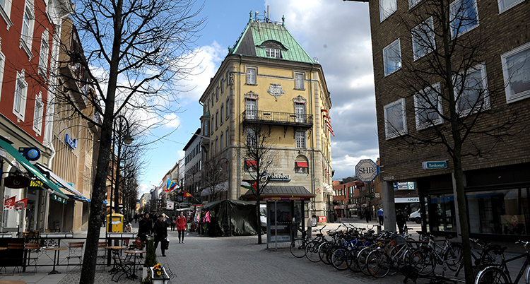 En gata i en stad med cyklar parkerade längs sidorna och ett beige hus i en vägkorsning