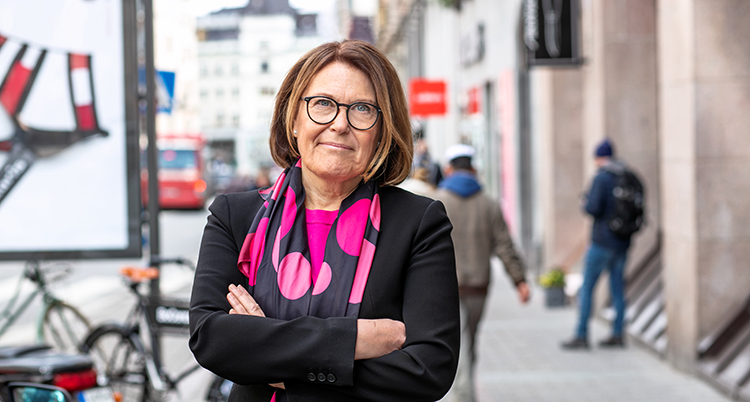 En kvinna står med armarna i kors utanför butiker