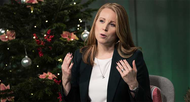 Annia Lööf pratar och lyfter båda händerna i en gest. Bakom henne står en julgran.