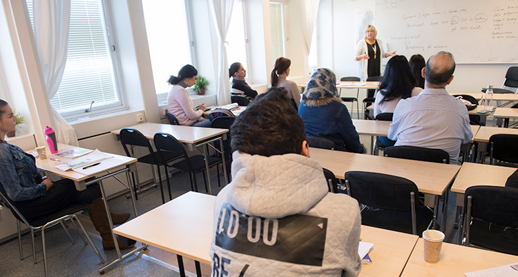 Elever sitter vid skolbänkar i ett klassrum