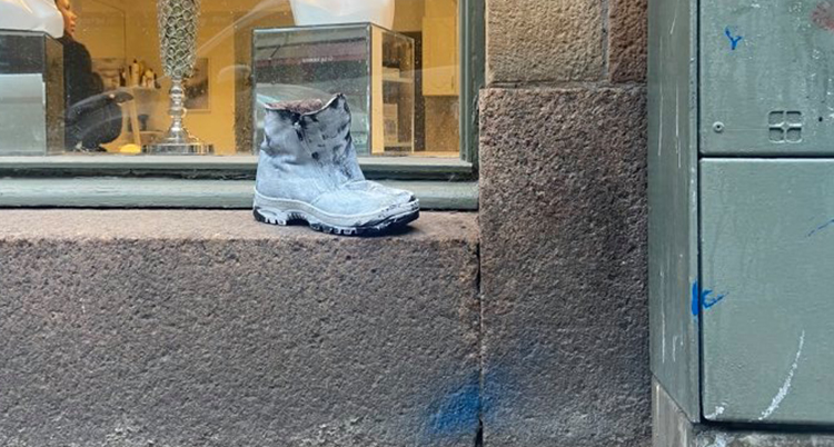 En vit sko står på utsidan av ett skyltfönster.