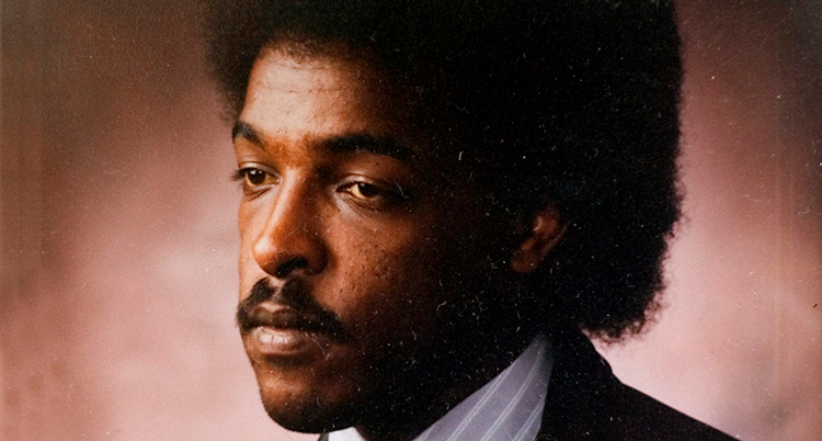 Ett gammalt porträtt på Dawit Isaak. Han ser allvarlig ut. Han tittar inte in i kameran. Han har stort svart hår och mustasch. Han har kavaj och skjorta.
