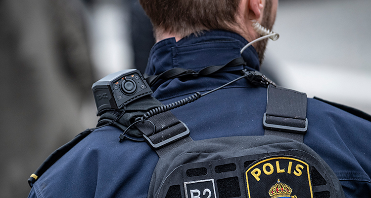 Bilden är en närbild på en polis. Bilden är tagen bakifrån. Vi ser nacken och ryggen på polisen.