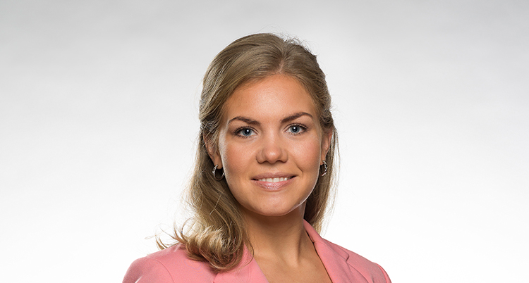Hon har rosa kavaj och blont långt hår.