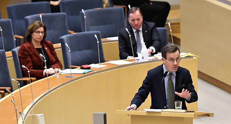Krister står i talarstolen och talar. I bankar bakom sitter Isabella Lövin och Stefan Löfven. De ser allvarliga ut.