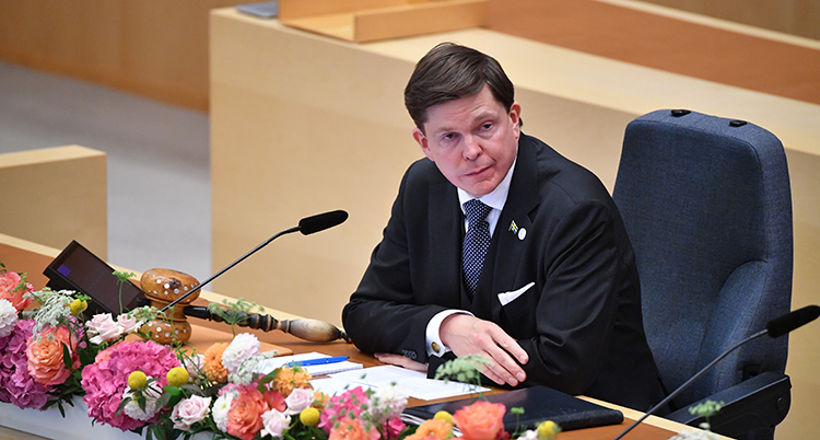 Riksdagens talman sitter i en stol vid sin plats i riksdagen