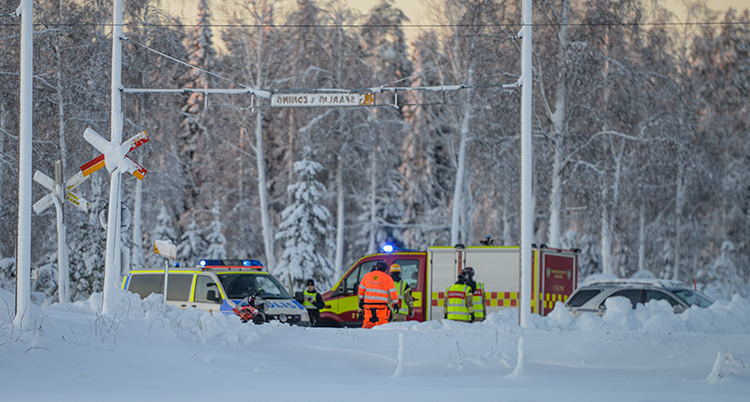 En polisbil och en räddningsbil syns vid tågrälsen. Det är mycket snö.