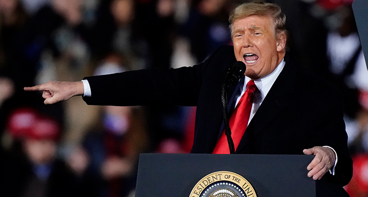 trump pratar i en talarstol. Han ser arg ut och pekar med ena handen rakt ut.