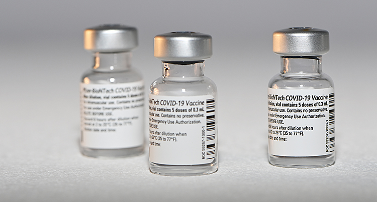 Tre små flaskor av glas. De har korkar av metall. Det är vaccin i flaskorna.