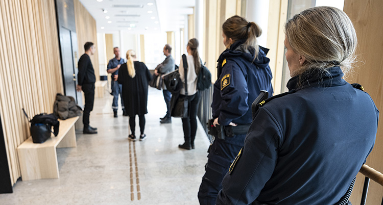 En korridor med människor. Två poliser syns.