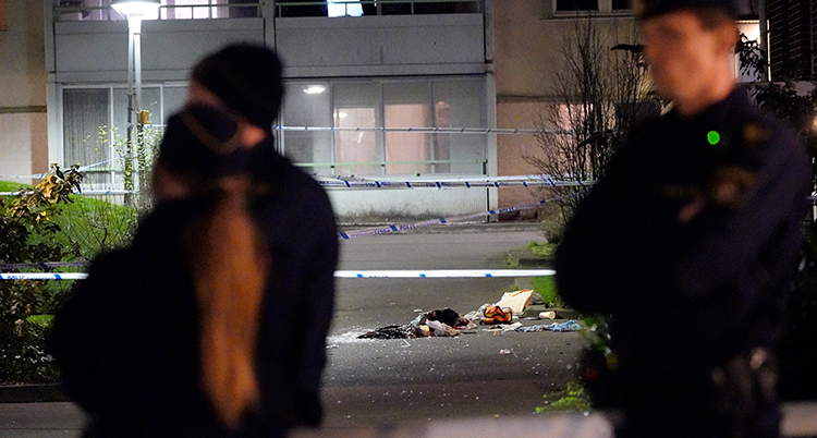 en avspärrad gata utanför ett hus. I förgrunden några poliser.