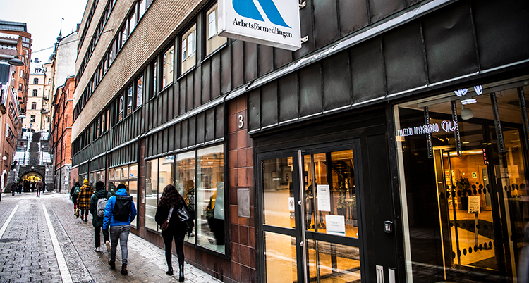 Några människor går på en trottoar utanför en arbetsförmedling