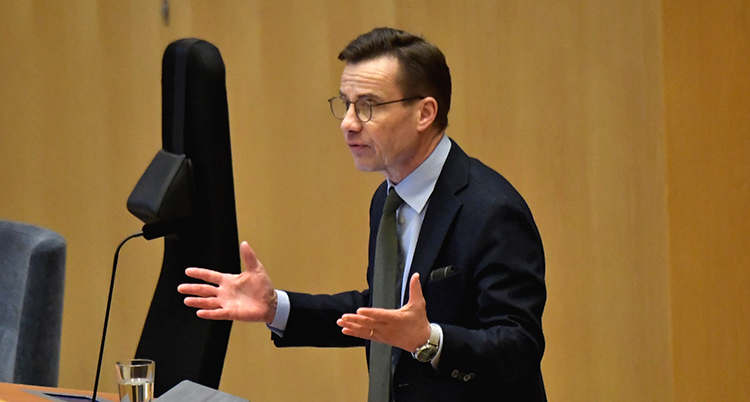 Kristersson står vid en mikrofon. Han är mitt i ett tal och slår ut med armarna. Han är engagerad.