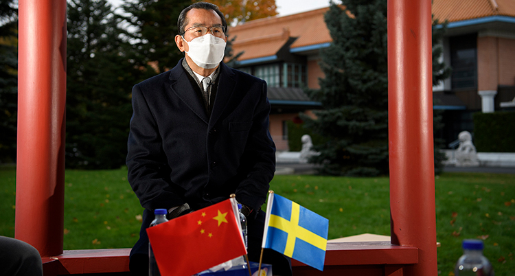 Ambassadören framför två små flaggor. En svensk flagga och en kinesisk.