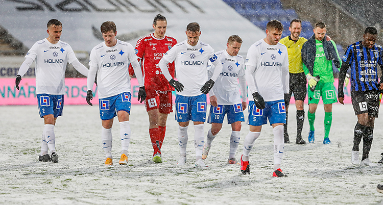 Från en match i fotboll. Matchen är slut. Spelarna är på väg av planen. Det snöar. Och det ligger snö på planen.