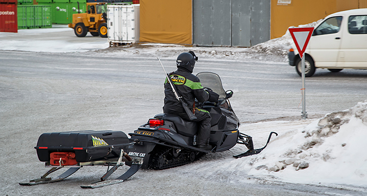 Bilden är tagen i Longyearbyn på Svalbard. Vi ser en skoter som kör på en vanlig väg.