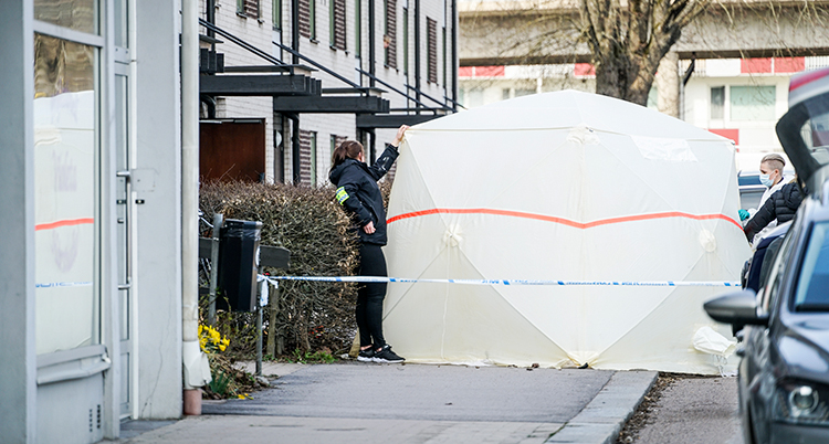 Poliser på ett gata med ett stort uppfällt vitt skynke eller tält.