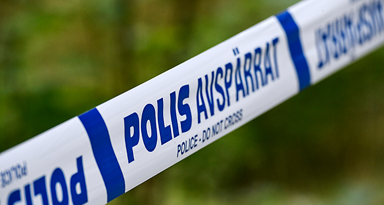 En närbild på ett band från poliserna. På bandet står det Polis Avspärrat. I bakgrunden syns en skog.