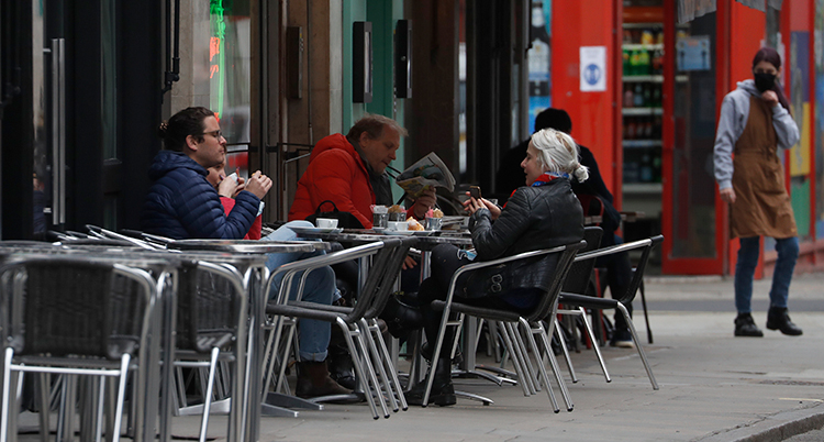 Några människor sitter vid ett bord på ett kafé. De sitter utomhus.